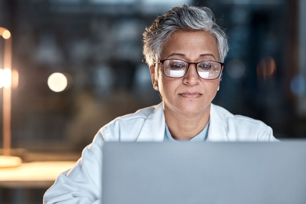 A doctor researches digitizing the wright competency assessment model on a laptop.