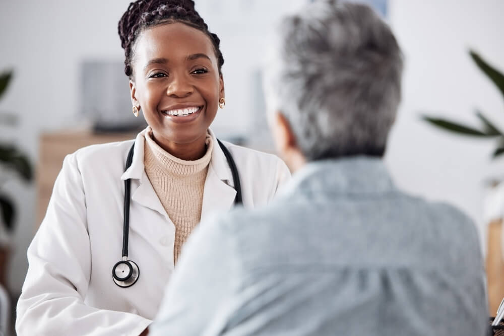 A doctor happily attends to an older patient.